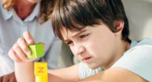 Image of young autistic boy staring at blocks.