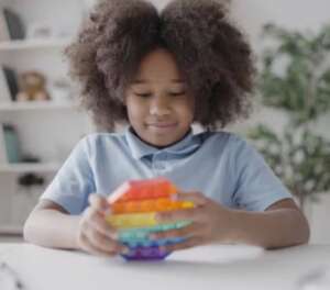 Image of young autistic girl using a pop-it fidget. 